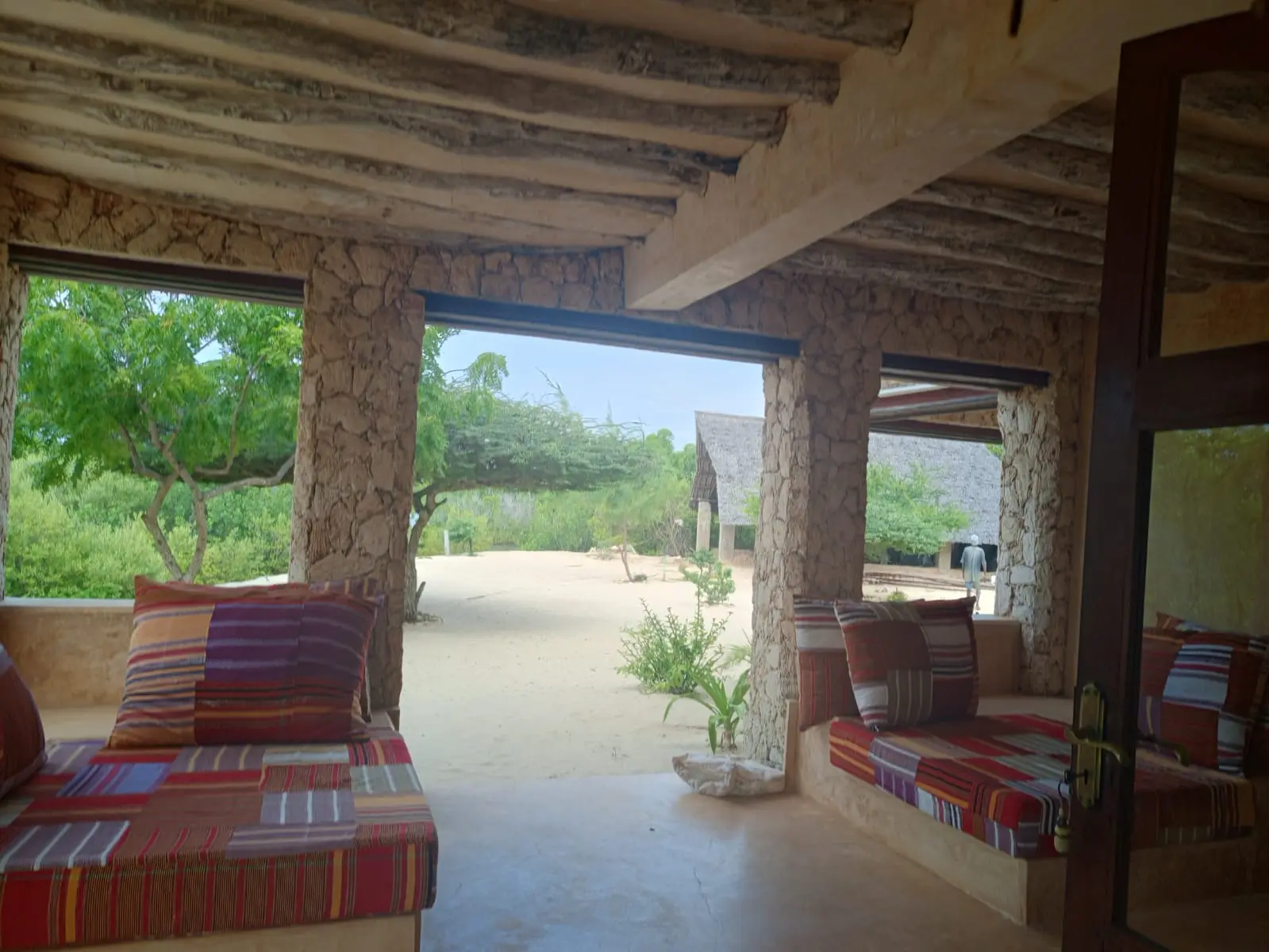 Covered terrace with coral stone columns and colorful striped seating