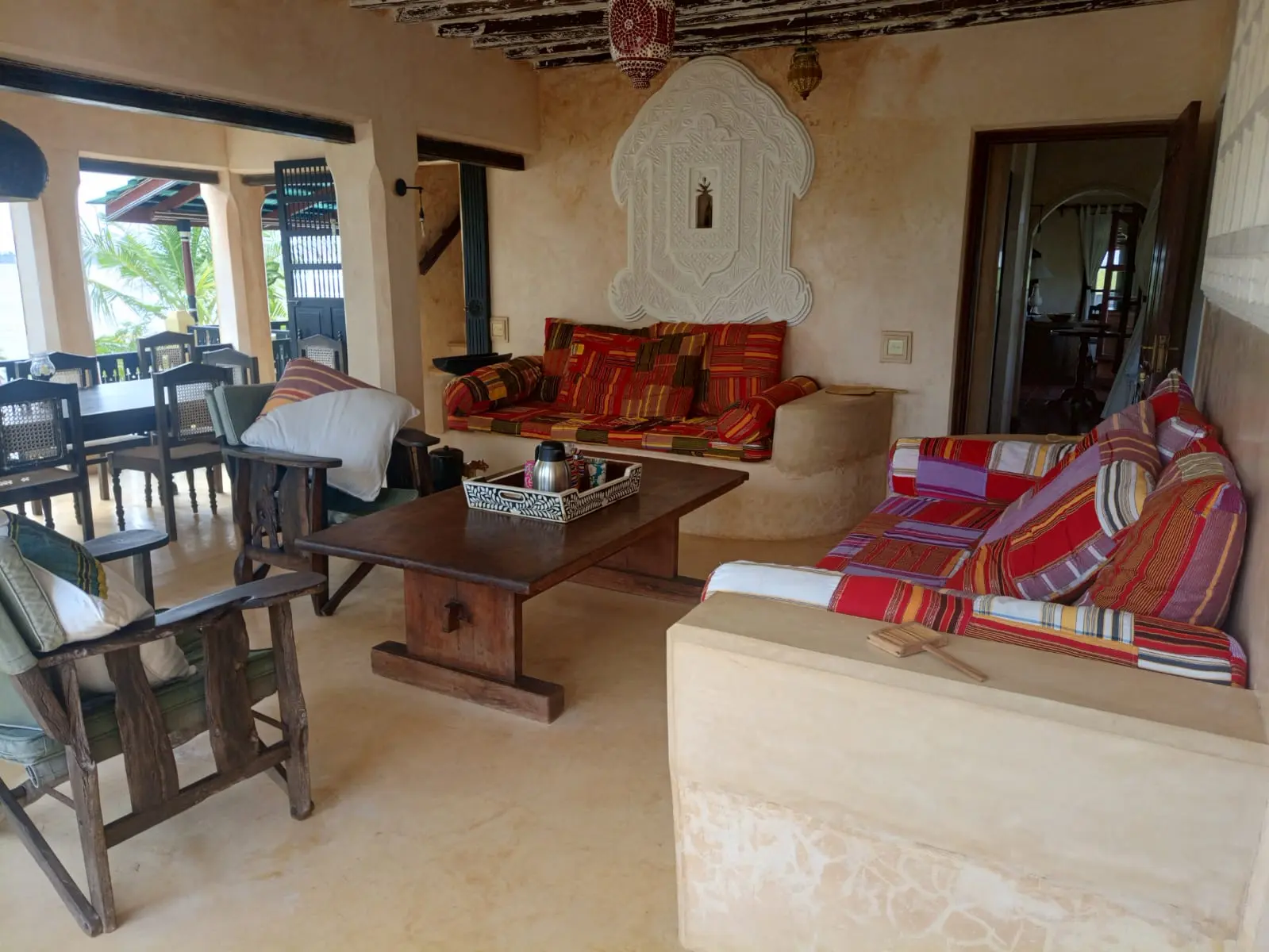 Living and dining area with colorful striped cushions and carved wall art