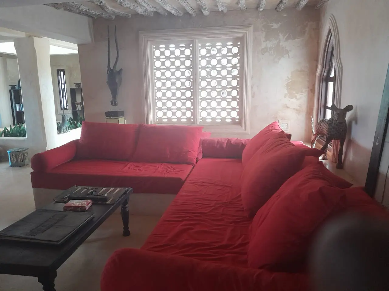 Spacious living room with red sectional sofa and traditional Swahili architecture